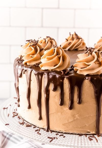 Close up photo of a layer cake with chocolate ganache dripping over the edge.