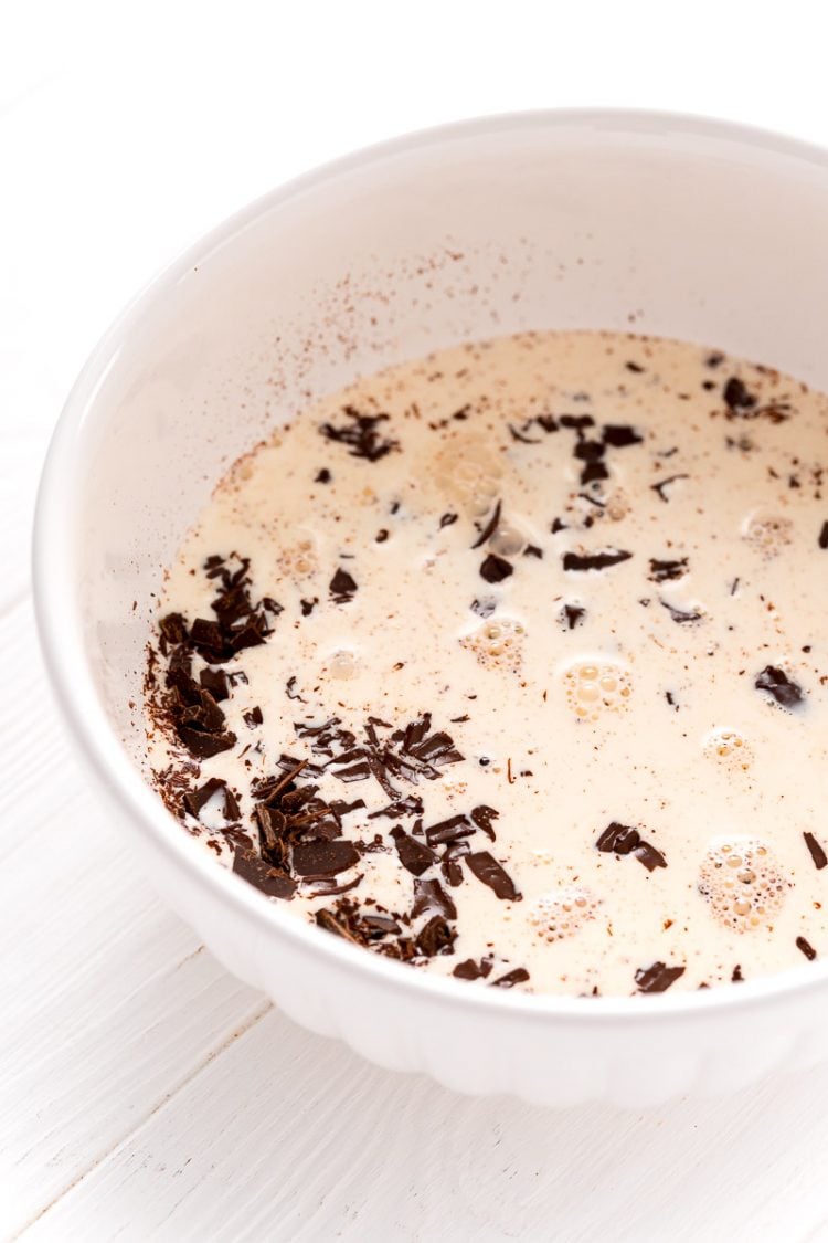 White bowl filled with chopped chocolate and heavy cream.