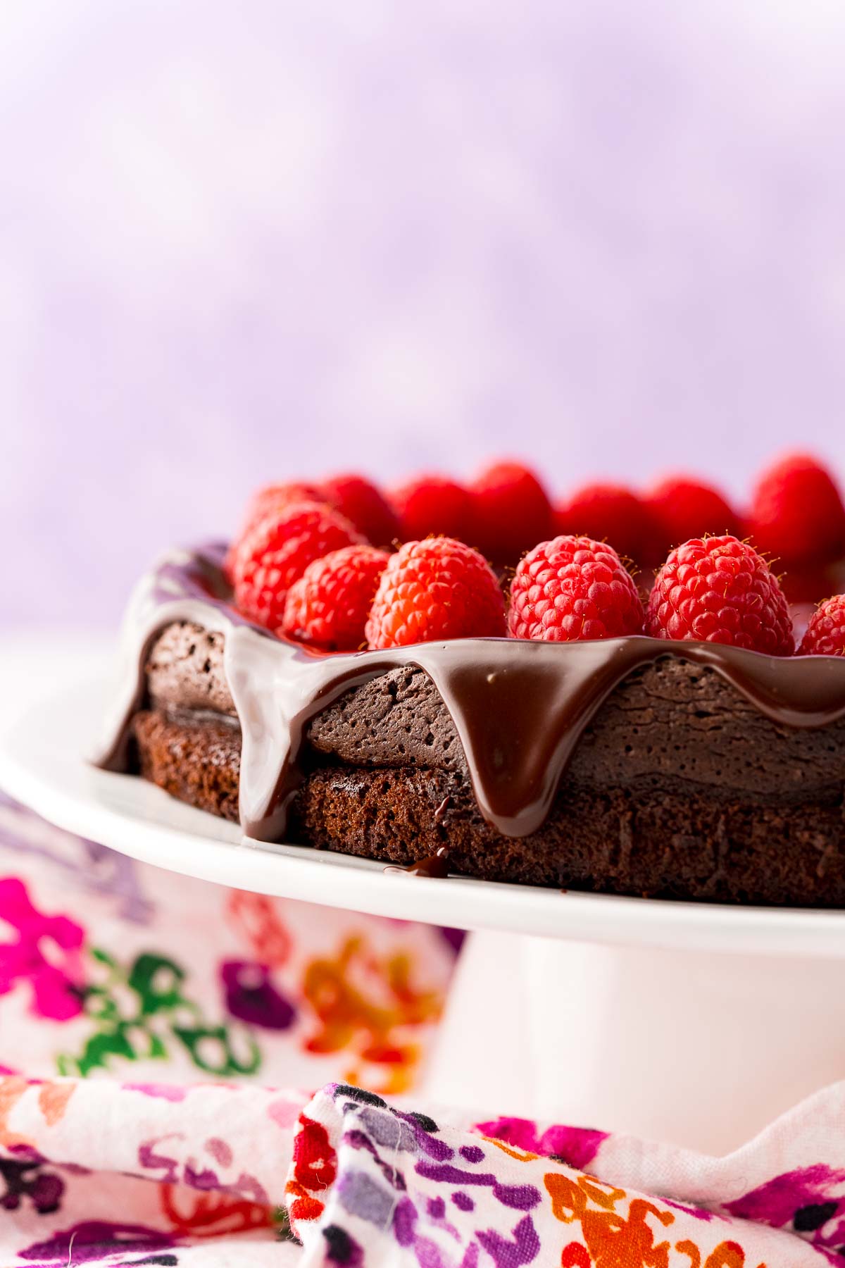 Close up photo of a flourless chocolate cake on a white cake stand.