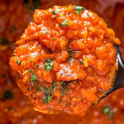 Close up photo of a ladle of marinara sauce.