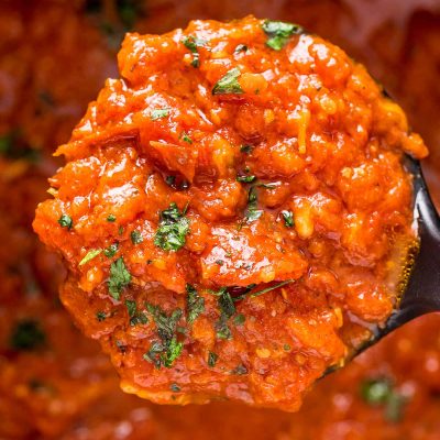 Close up photo of a ladle of marinara sauce.