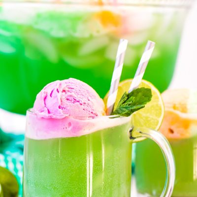 Close up photo of a clear mug filling with green punch.