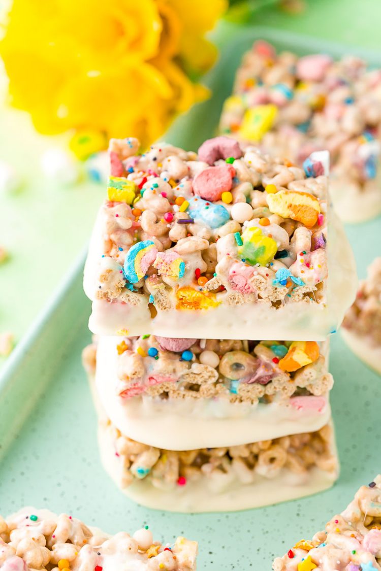 Three lucky charms treats stacked on top of each other on a blue cookie sheet.
