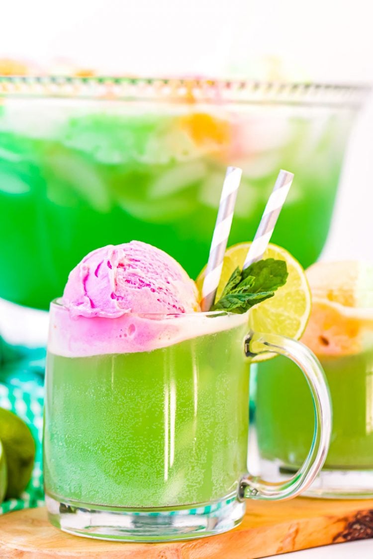 Close up photo of a clear mug filling with green punch.