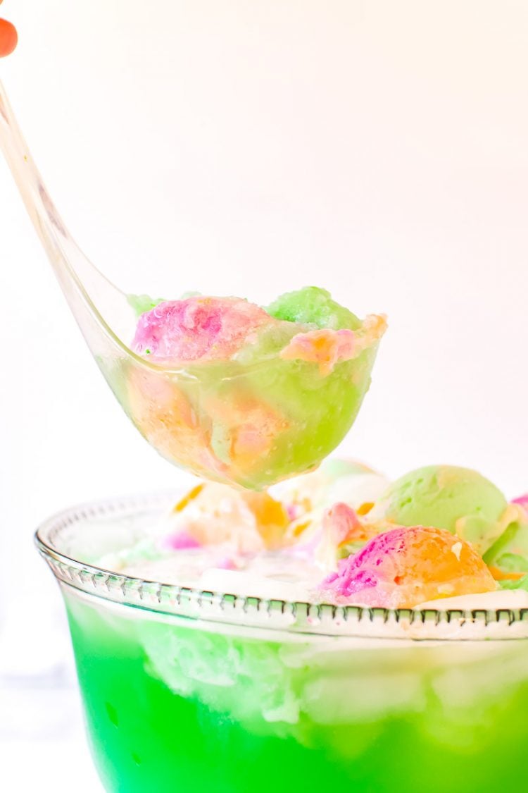 A ladle scooping green punch out of a bowl.