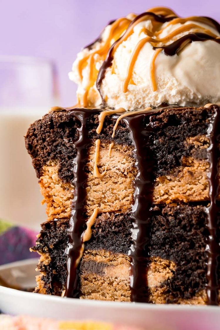 Close up photo of two brownies stacked on top of each other topped with ice cream and drizzled with chocolate and peanut butter.