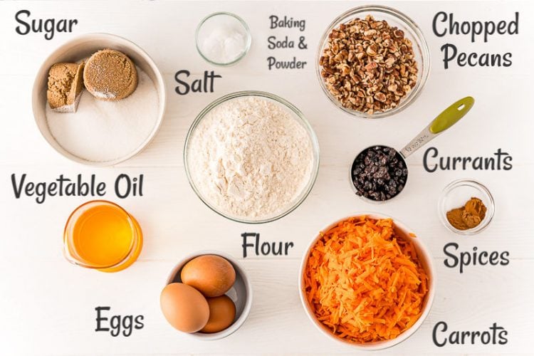 Overhead photo of ingredients to make carrot cake in prep bowls on a white table.