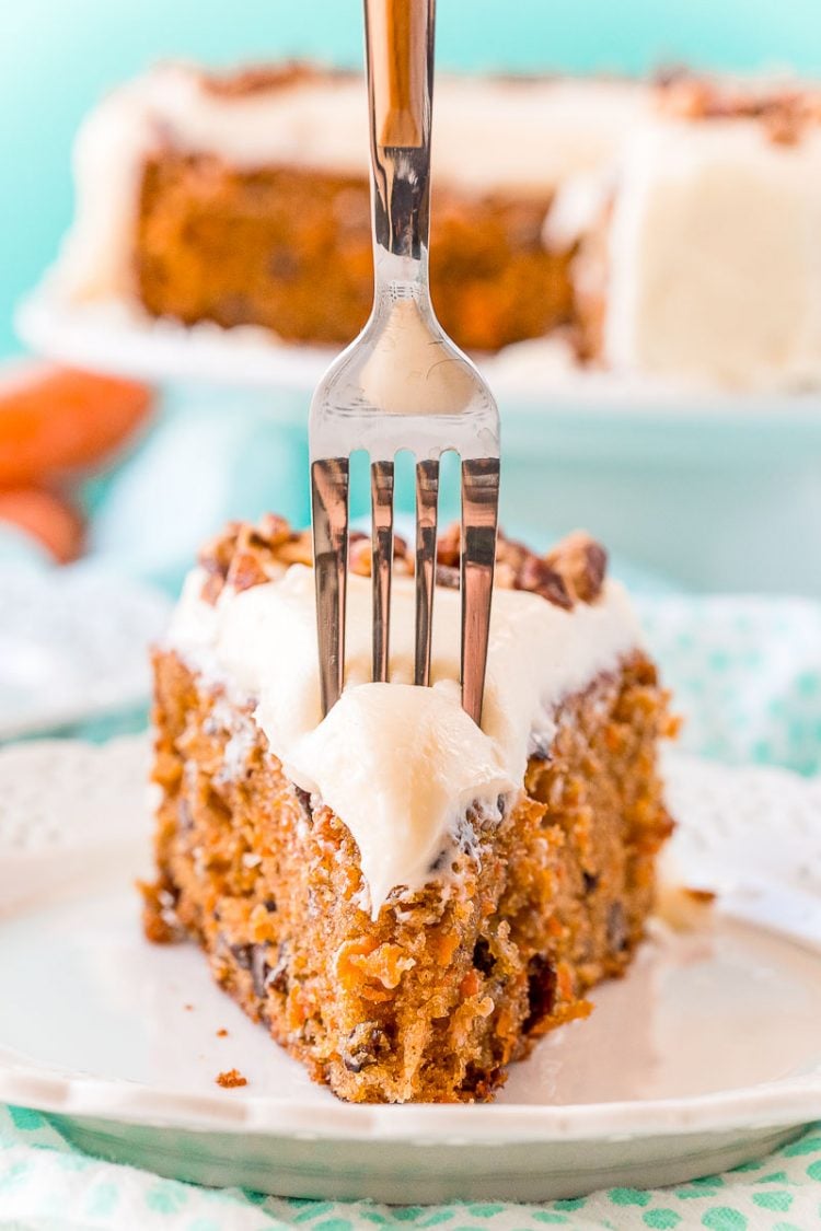 Fork taking a bite out of a slice of carrot cake.