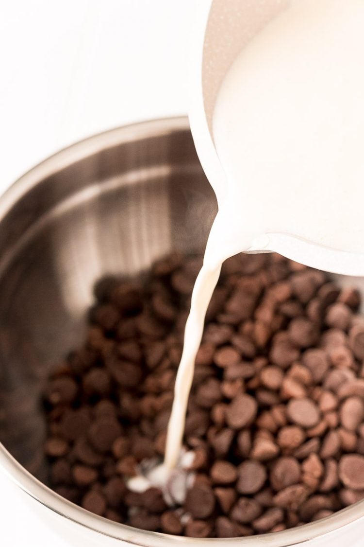 Warm cream being poured into a bowl with chocolate chips.