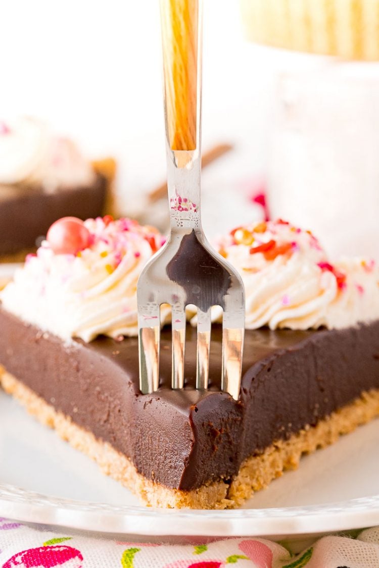 A fork taking a bite out of a chocolate tart.