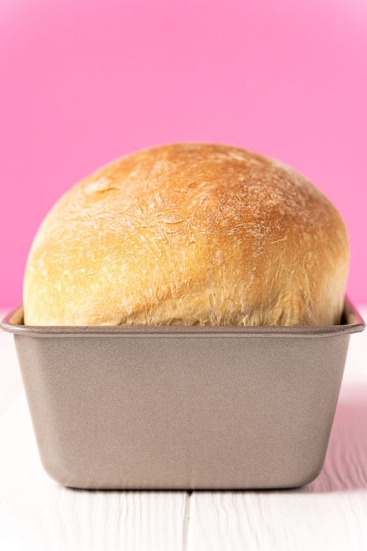 baked loaf of bread in a bread pan on a white table.