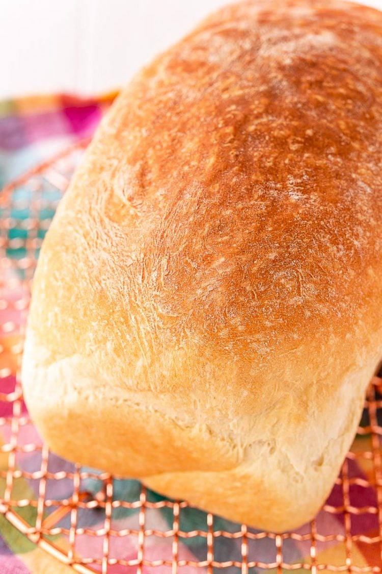 Load of bread sitting on a wire rack on a colorful napkin.