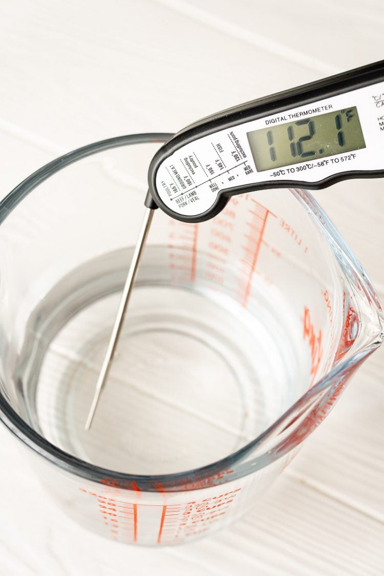 Digital thermometer in a measuring cup of water.