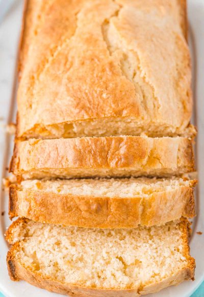 Loaf of bread on a white cutting board partially sliced.