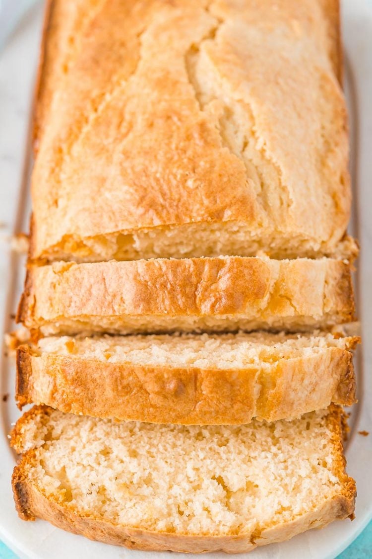 Loaf of bread on a white cutting board partially sliced.