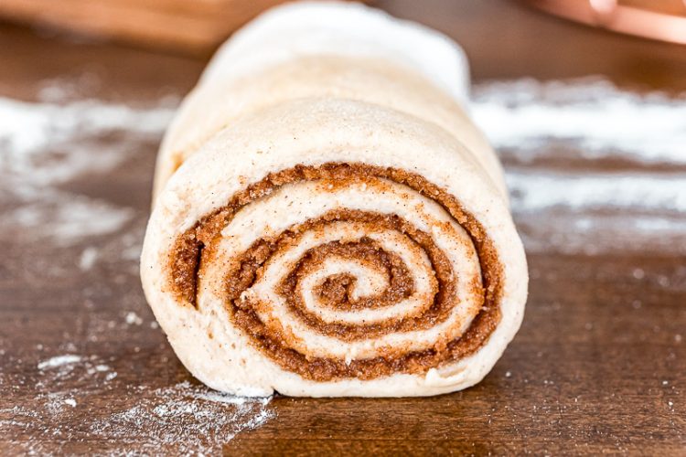 Unbaked cinnamon rolls being sliced.