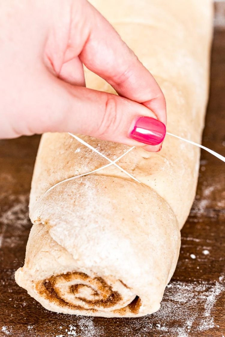 Woman slicing cinnamon rolls with floss.