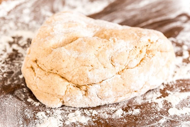 Dough for making cinnamon rolls resting on a floured surface.