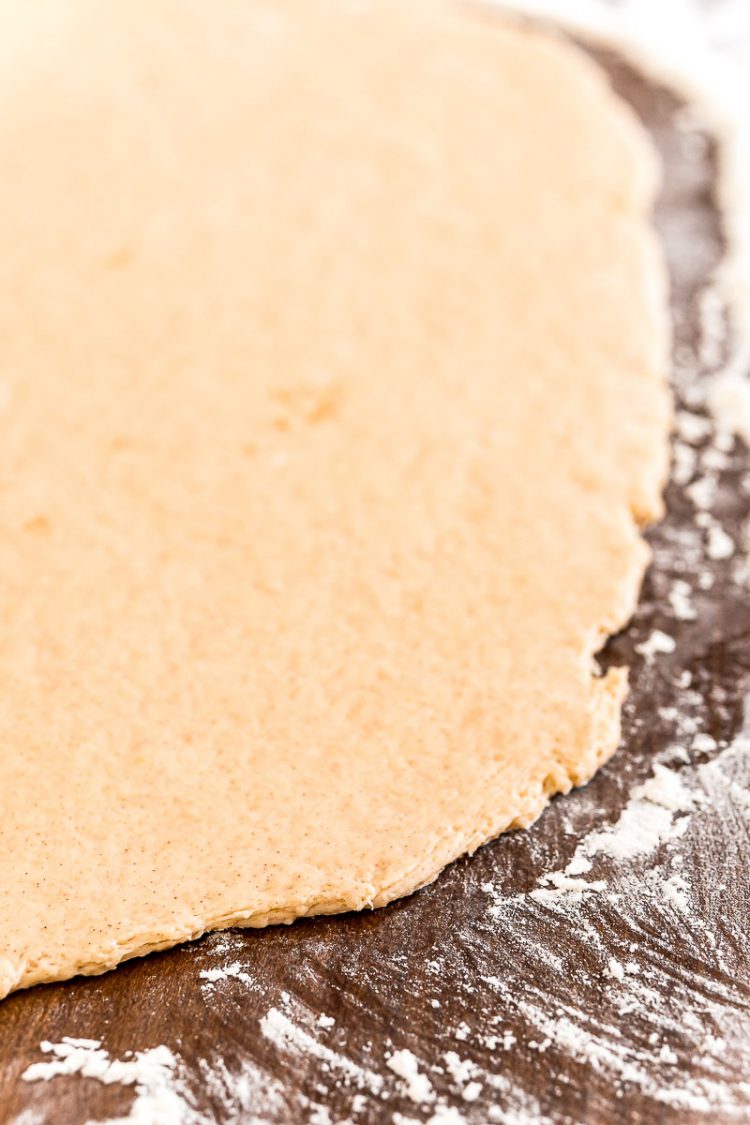 Cinnamon roll dough rolled out on a floured surface.