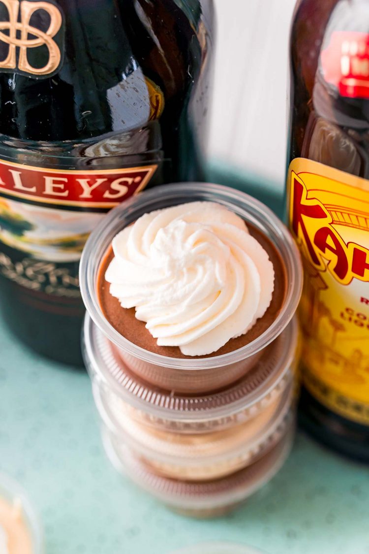 Close up photo of a stack of pudding shots between two bottles of liqueur.