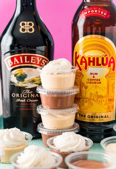 Stack of pudding shots between a bottle of Baileys and a bottle of Kahlua.