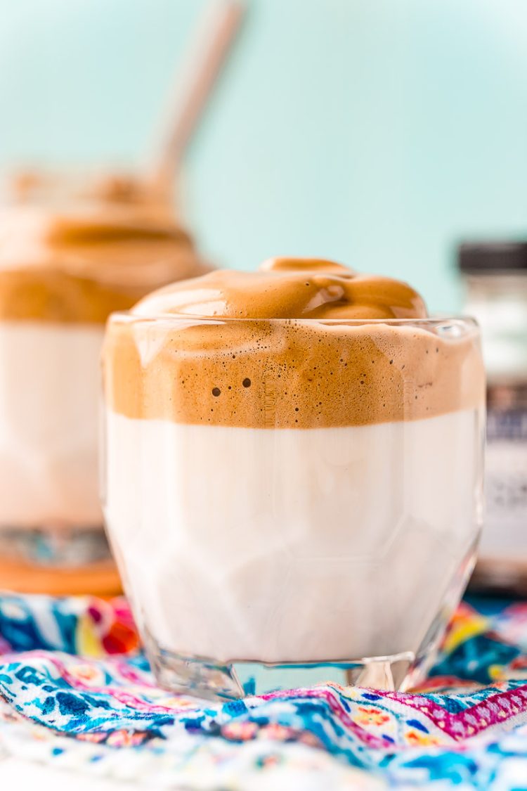 Glass of whipped coffee on a blue patterned napkin.