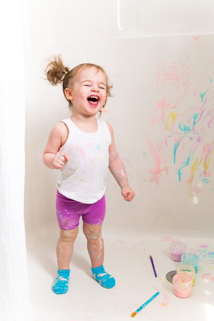 Toddler girl painting with bath paints.