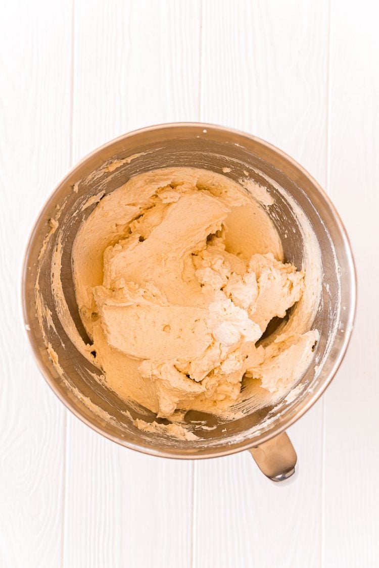 Cookie dough being mad in a stand mixer bowl.