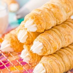 Six cream horns stacked on top of each other on a wire rack.