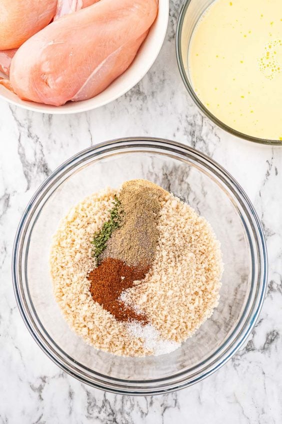 Breadcrumbs and seasonings in a glass prep bowl for breading chicken.