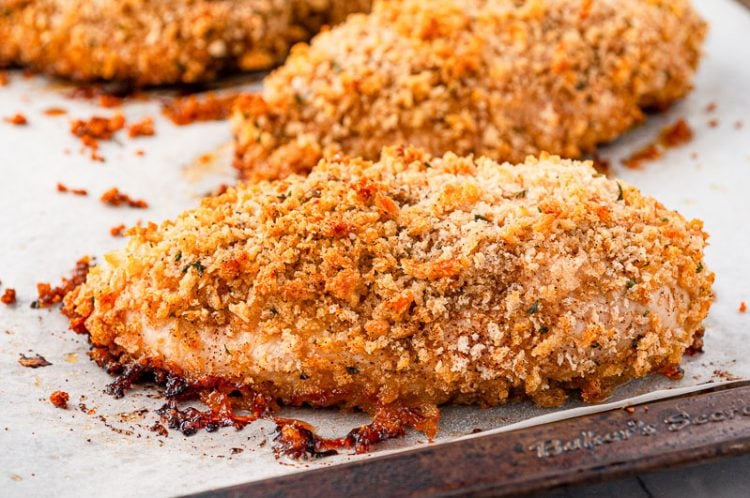 Oven friend chicken breast sitting on a baking sheet lined with parchment paper.