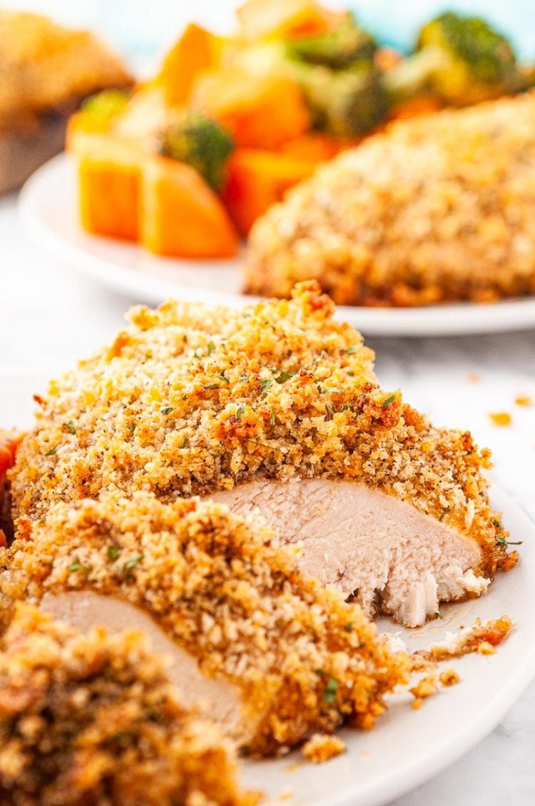 Breaded chicken breast sliced on a white plate.