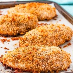 Baked chicken breast on a sheet pan that's been breaded.