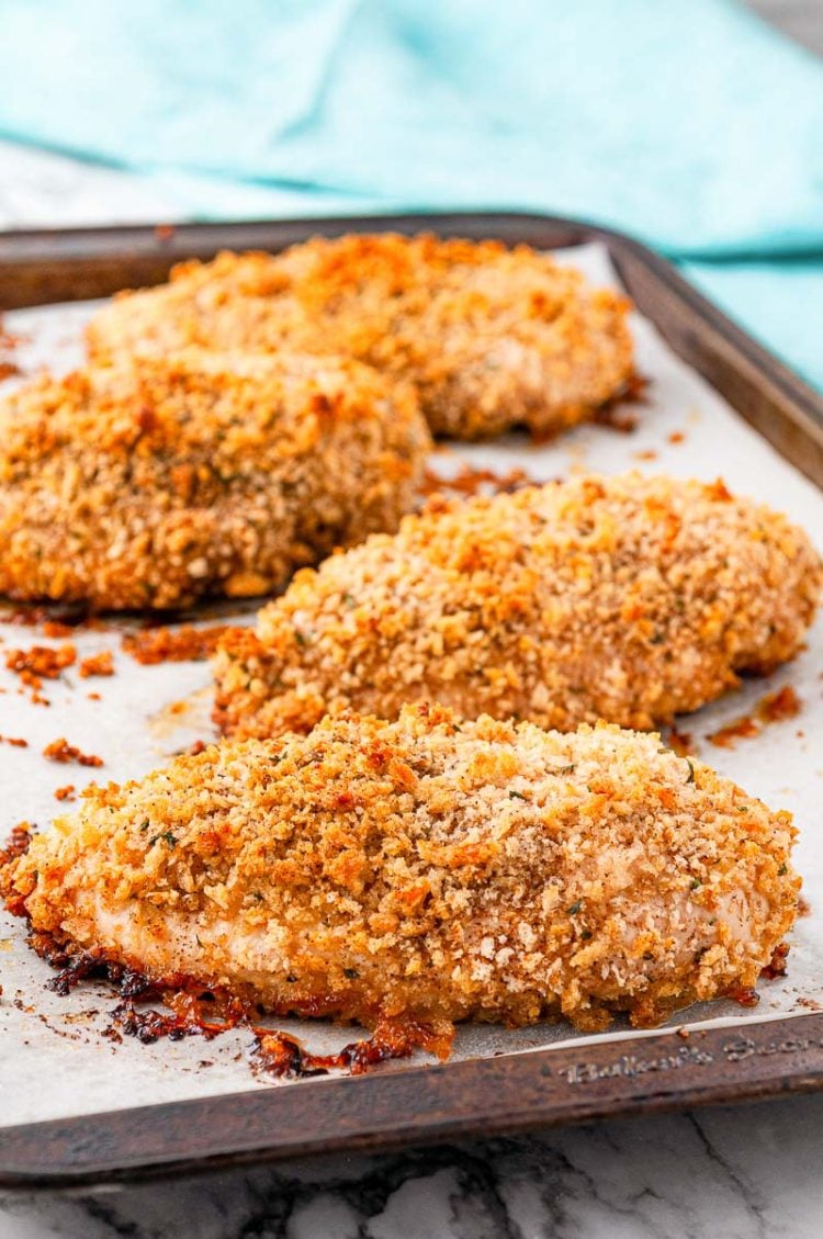 Baked chicken breast on a sheet pan that's been breaded.