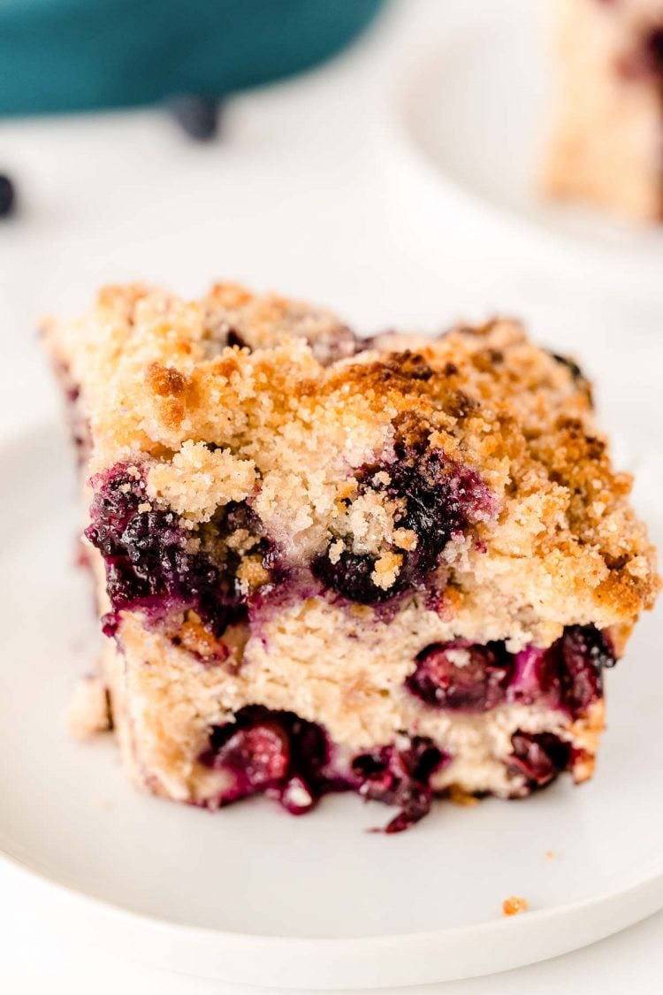 Slice of blueberry buckle on a white plate.