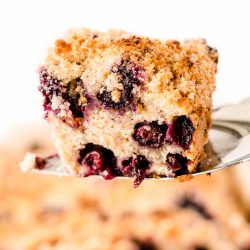 A spatula lifting a slice of blueberry buckle out of the pan.