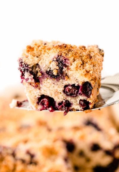 A spatula lifting a slice of blueberry buckle out of the pan.