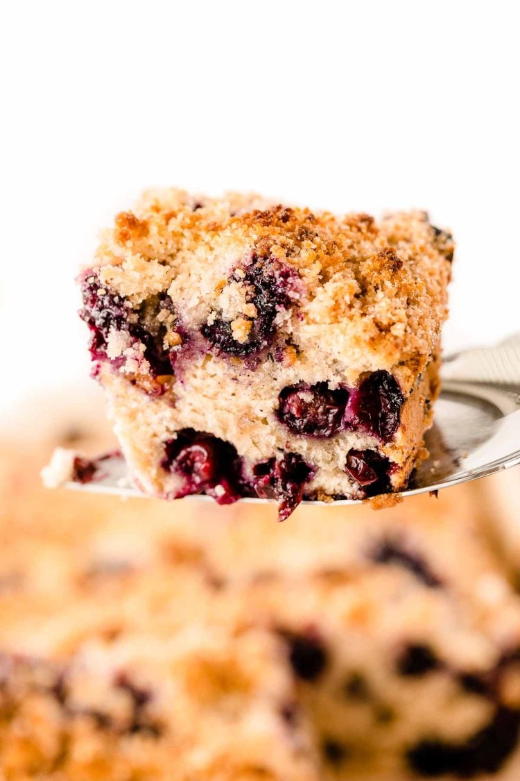 A spatula lifting a slice of blueberry buckle out of the pan.