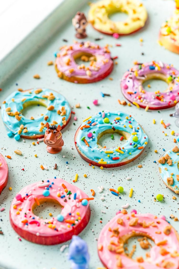 Apple donut slices on a blue serving tray with sprinkles.