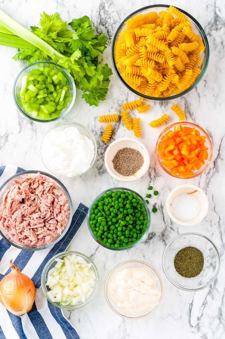 Overhead photo of ingredients prepped to make a pasta salad on a marble surface.