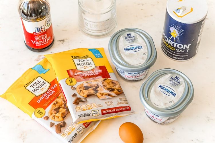 Ingredients to make chocolate chip cheesecake bars on a white table.