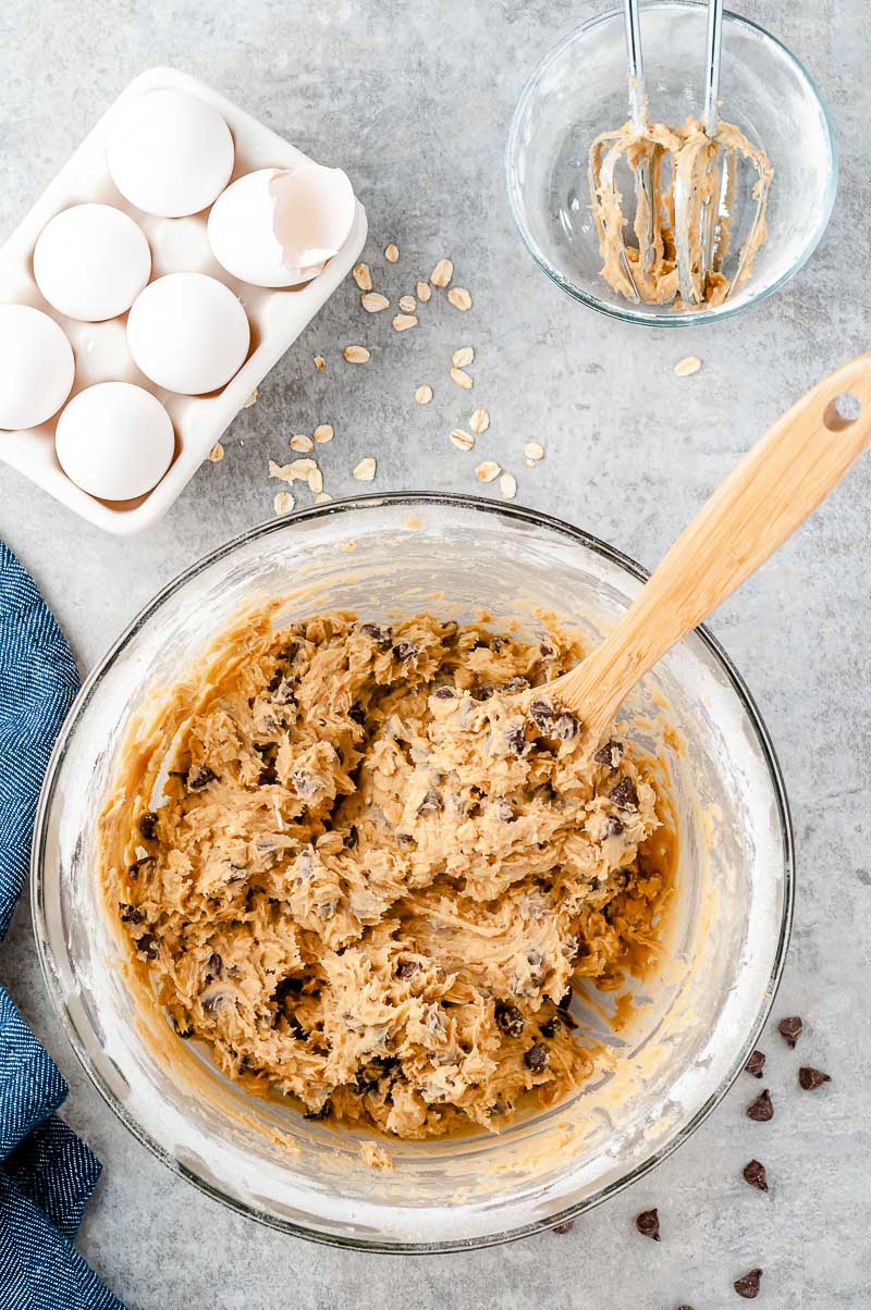 Overhead photo of a bowl of cookie dough on a grey surface.