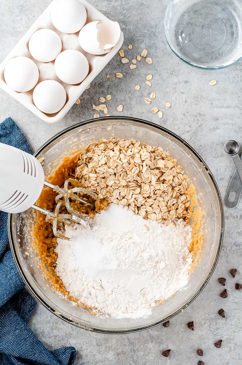 Dry ingredients being added to a bowl of wet ingredients for making cookies.