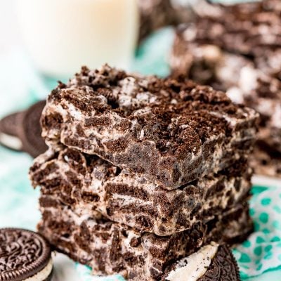 Three marshmallow oreo treats stacked on top of each other on a teal napkin.