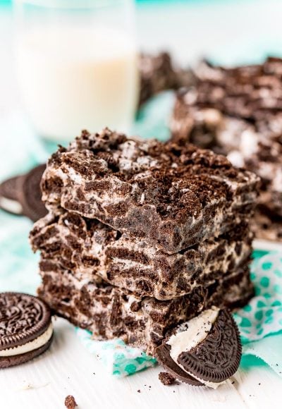 Three marshmallow oreo treats stacked on top of each other on a teal napkin.