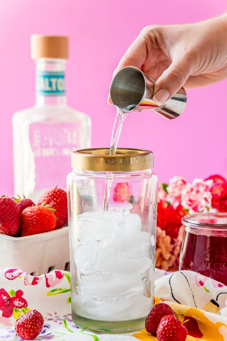 Tequila being added to a cocktail shaker.