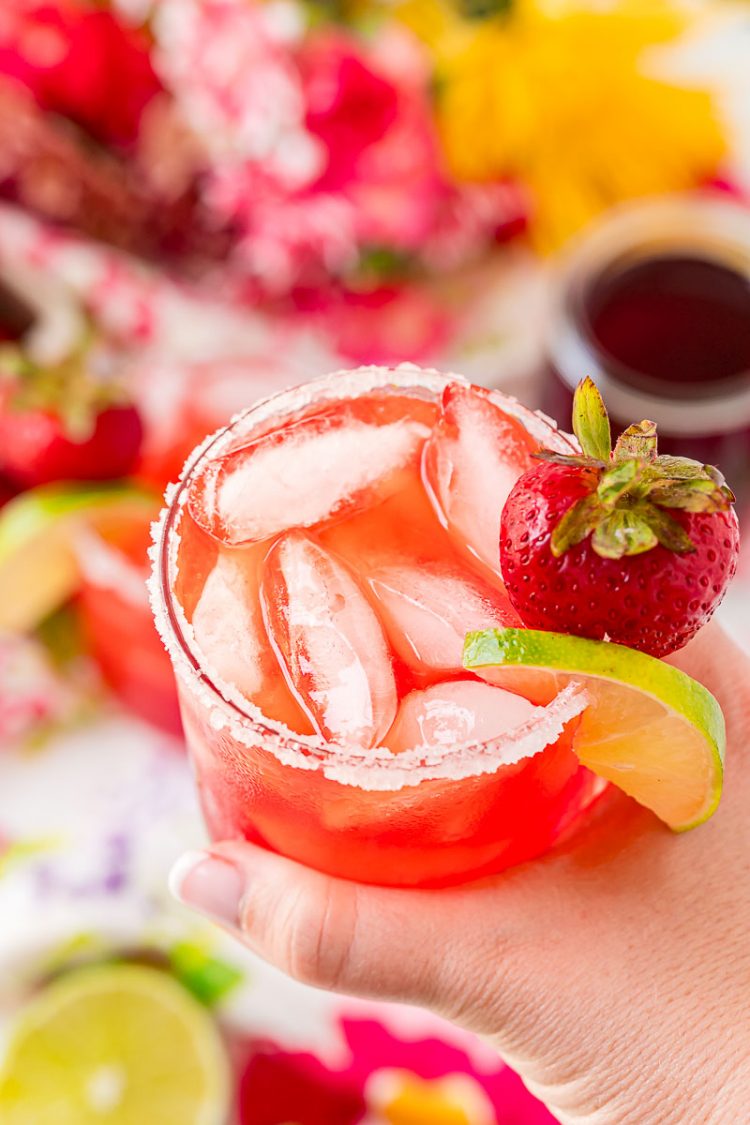 Woman's hand holding a strawberry margarita.