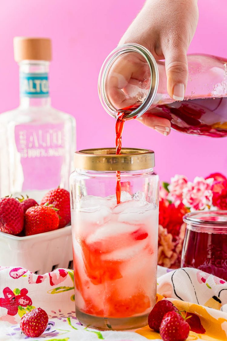 Strawberry simple syrup being added to a cocktail shaker.