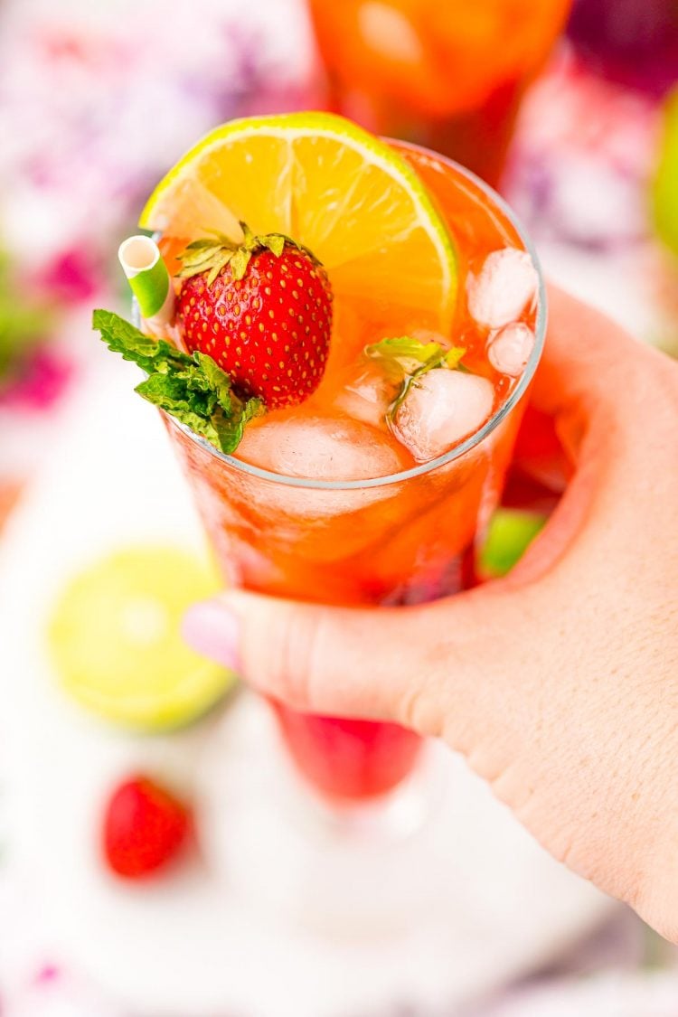 A woman's hand holding a strawberry mojito.