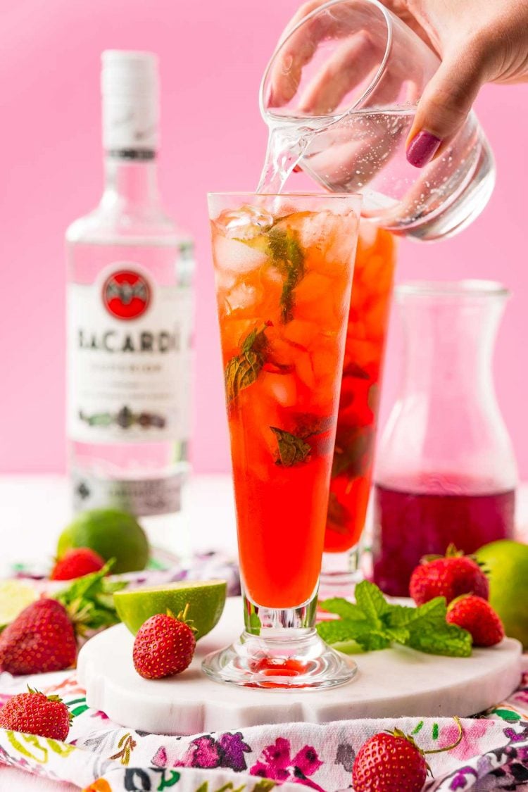 Club soda being added to a strawberry mojito.